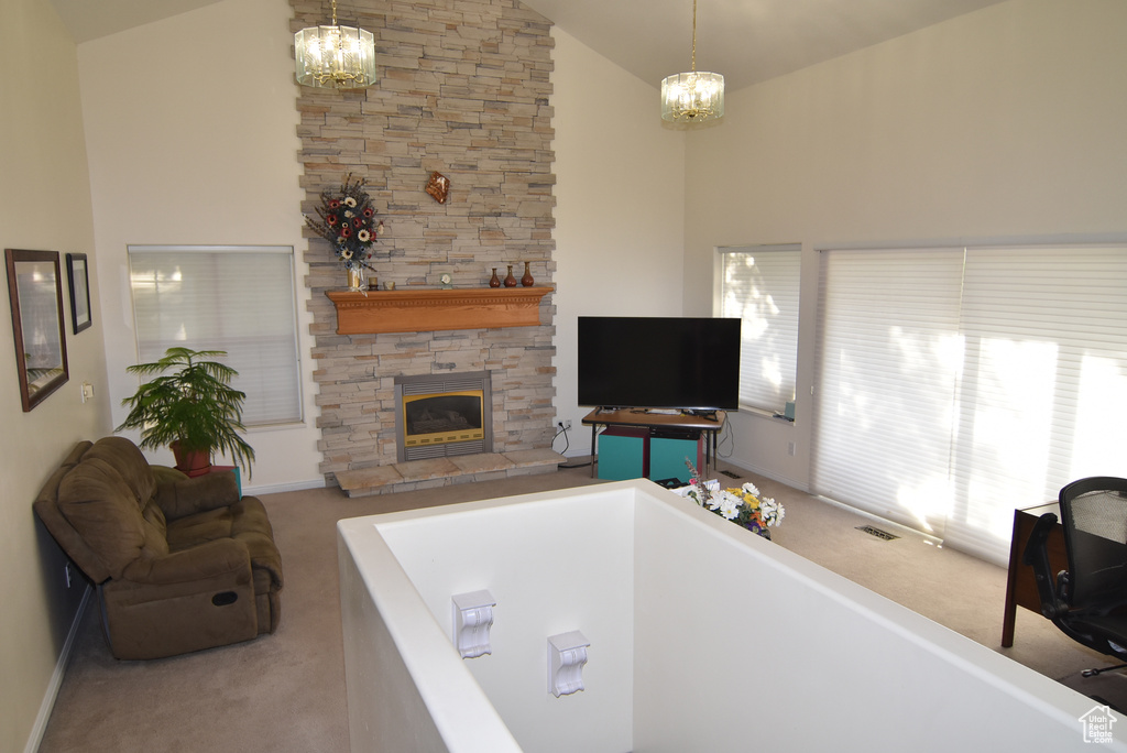 Carpeted living area with a chandelier, high vaulted ceiling, a fireplace, and baseboards