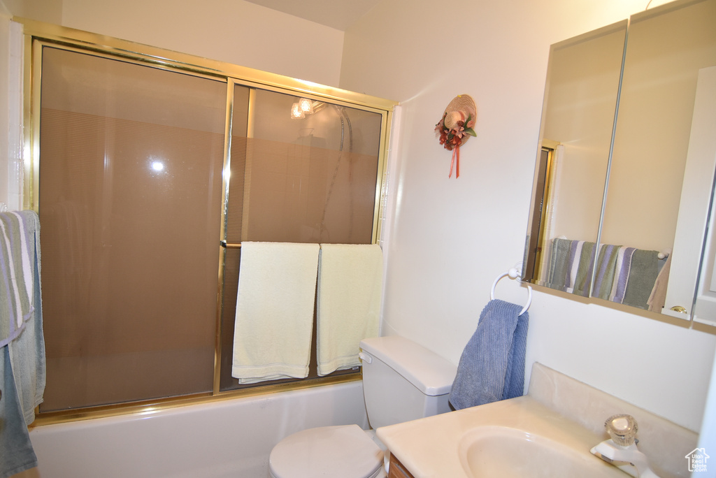Bathroom with toilet, combined bath / shower with glass door, and vanity
