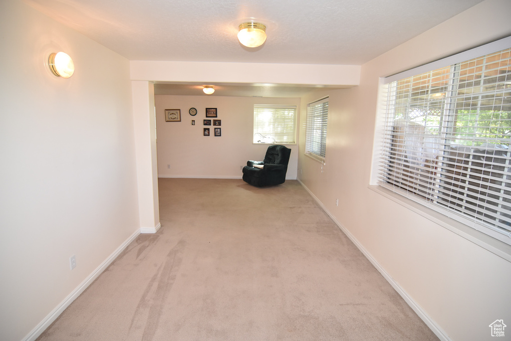 Hallway with light colored carpet and baseboards