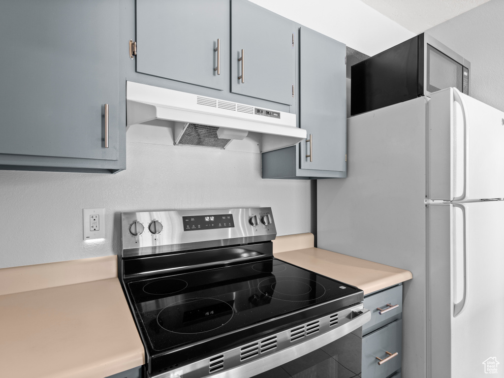 Kitchen featuring gray cabinets, light countertops, electric range, and under cabinet range hood