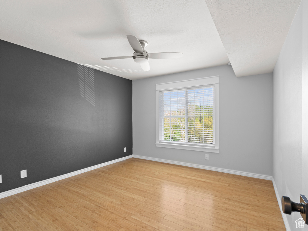 Empty room featuring a ceiling fan, baseboards, and light wood finished floors