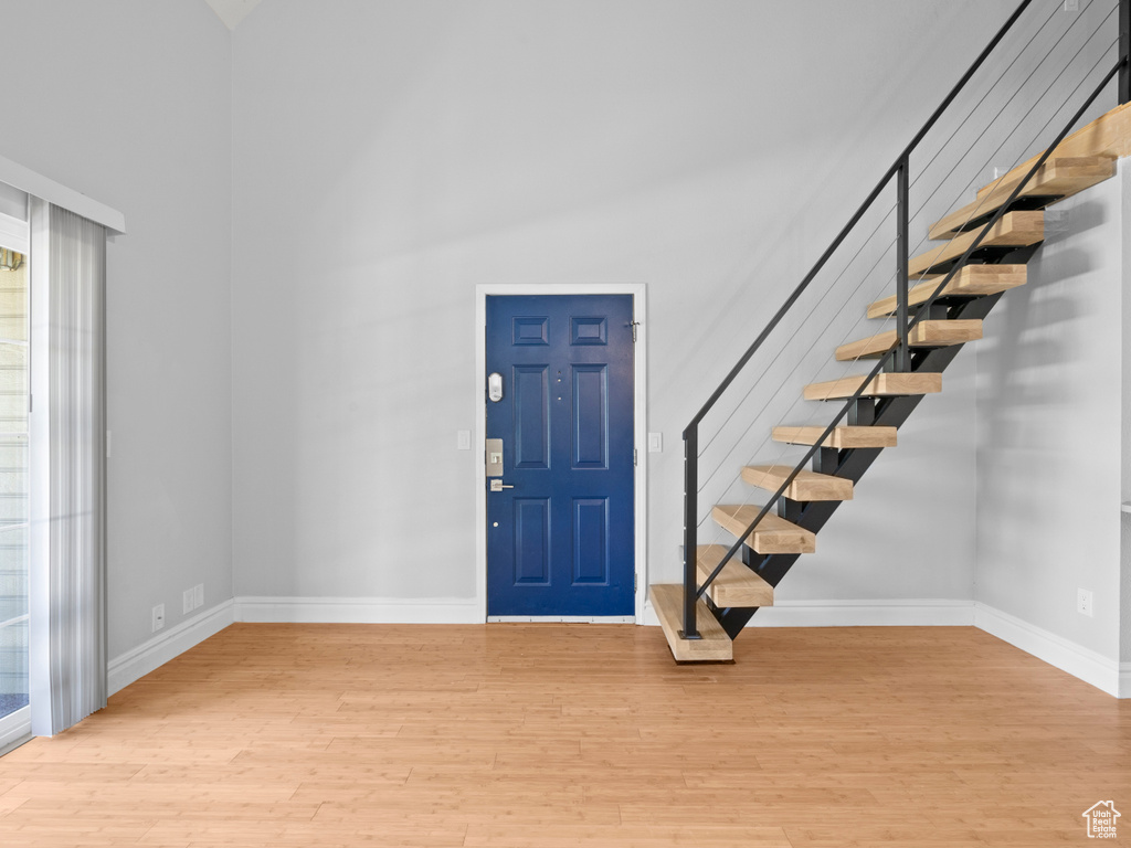 Entrance foyer featuring stairs, baseboards, wood finished floors, and a towering ceiling