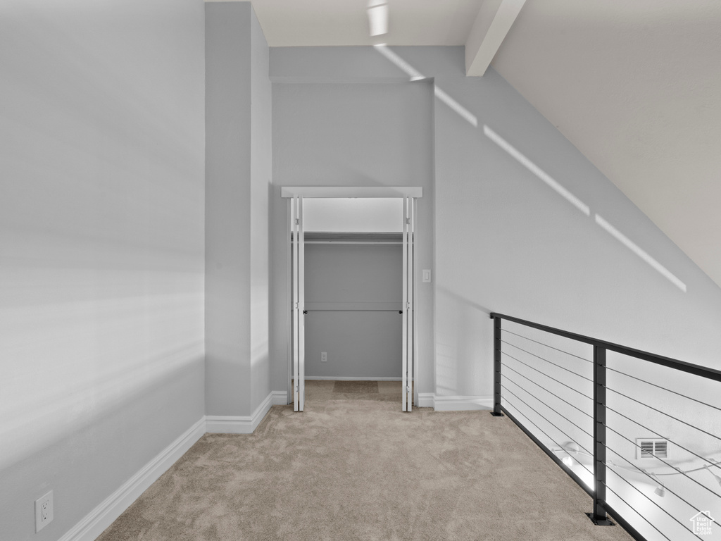 Interior space featuring lofted ceiling with beams, baseboards, carpet, and a closet