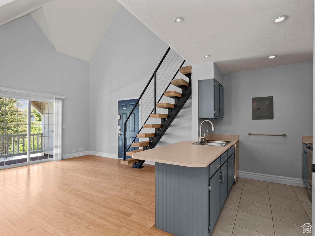 Kitchen with electric panel, a sink, baseboards, light countertops, and a peninsula