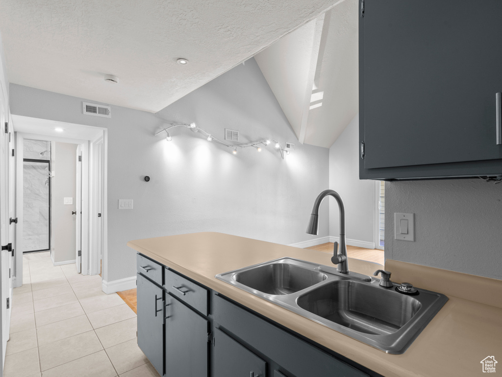 Kitchen with light tile patterned floors, a textured ceiling, visible vents, and a sink