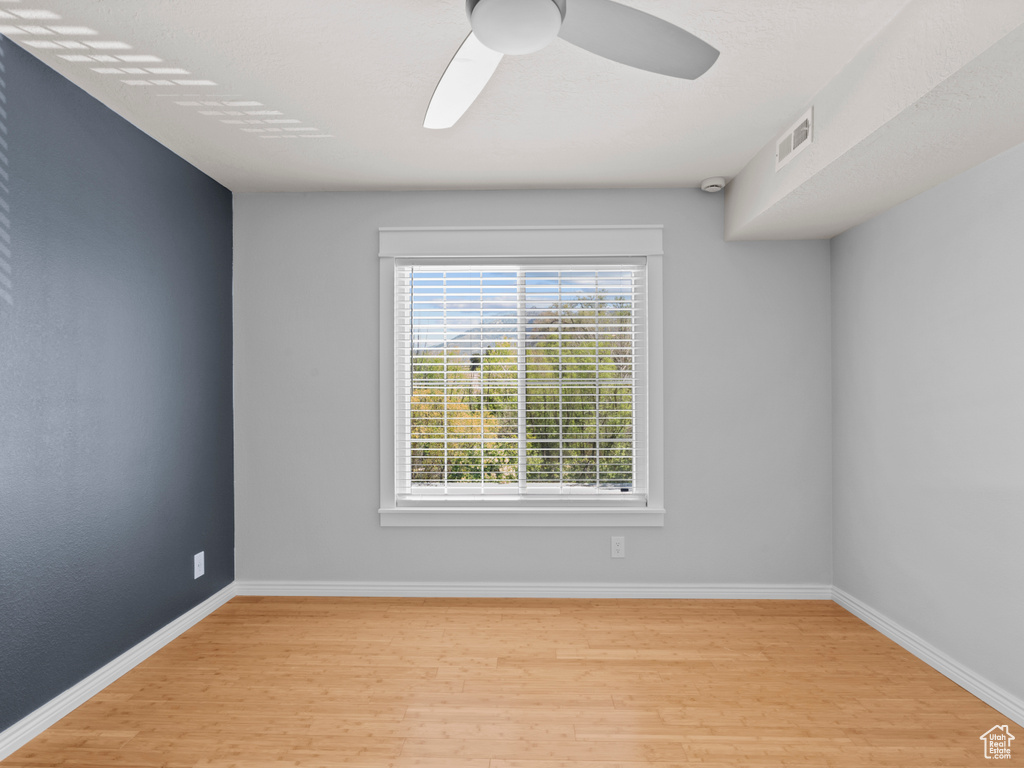 Spare room with visible vents, a ceiling fan, light wood-style floors, and baseboards