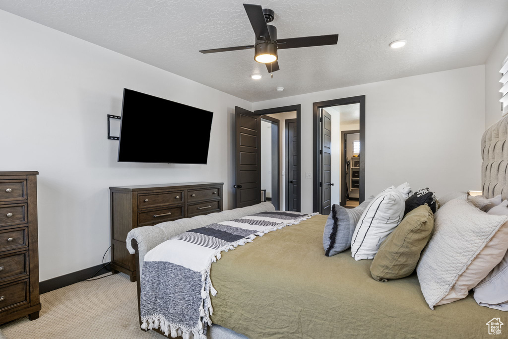 Bedroom featuring baseboards, a textured ceiling, ceiling fan, and light carpet