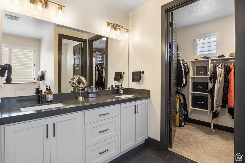 Bathroom featuring a walk in closet, visible vents, a sink, and tile patterned flooring