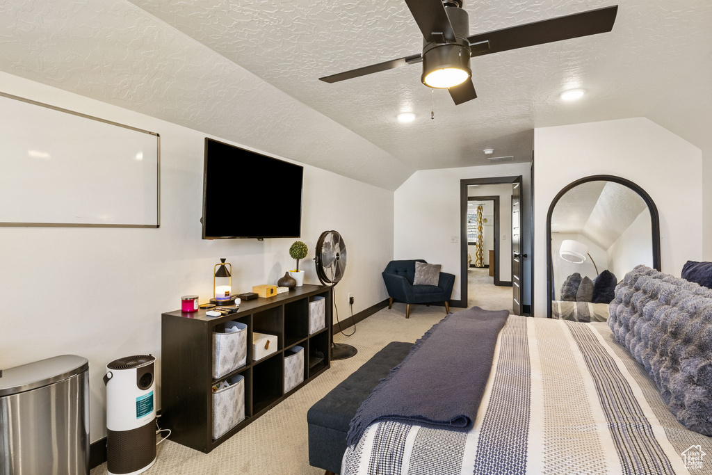 Bedroom featuring light colored carpet, a textured ceiling, and lofted ceiling