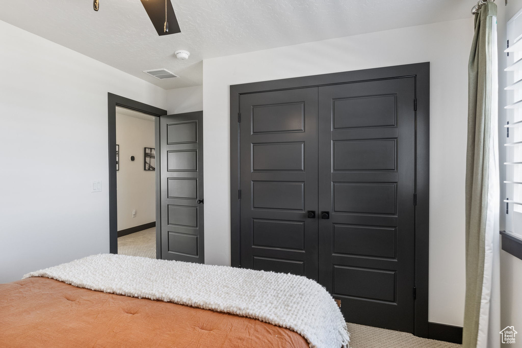 Bedroom with a ceiling fan, visible vents, baseboards, a closet, and light carpet