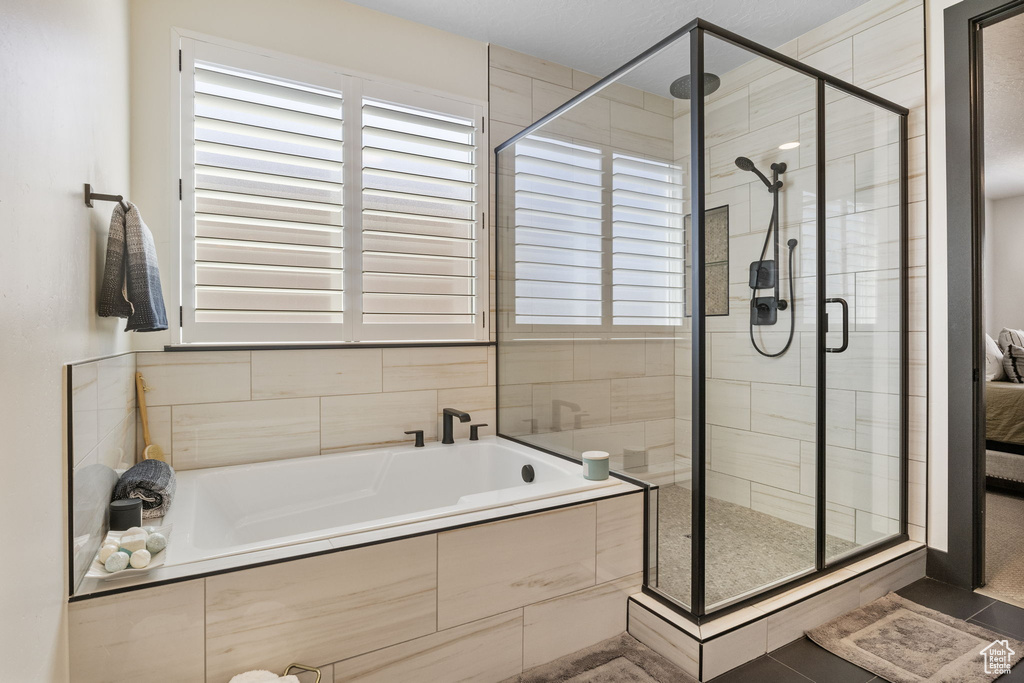 Bathroom featuring tile patterned floors, plenty of natural light, a bath, and a stall shower