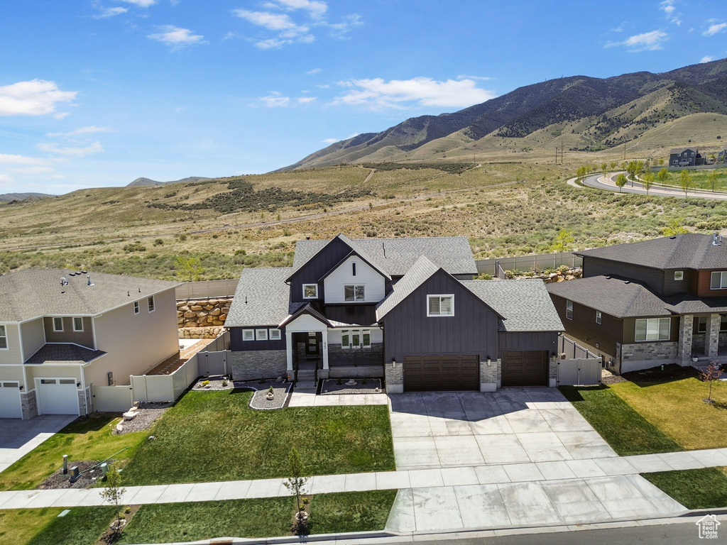 Exterior space with an attached garage, board and batten siding, driveway, and stone siding