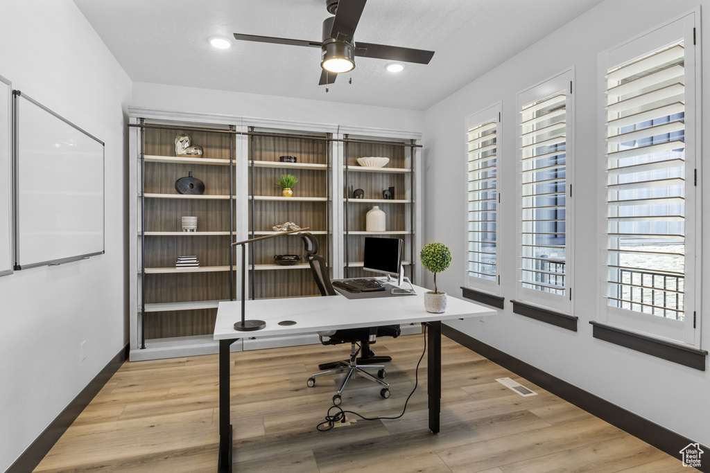 Office space featuring a ceiling fan, visible vents, light wood-type flooring, baseboards, and recessed lighting