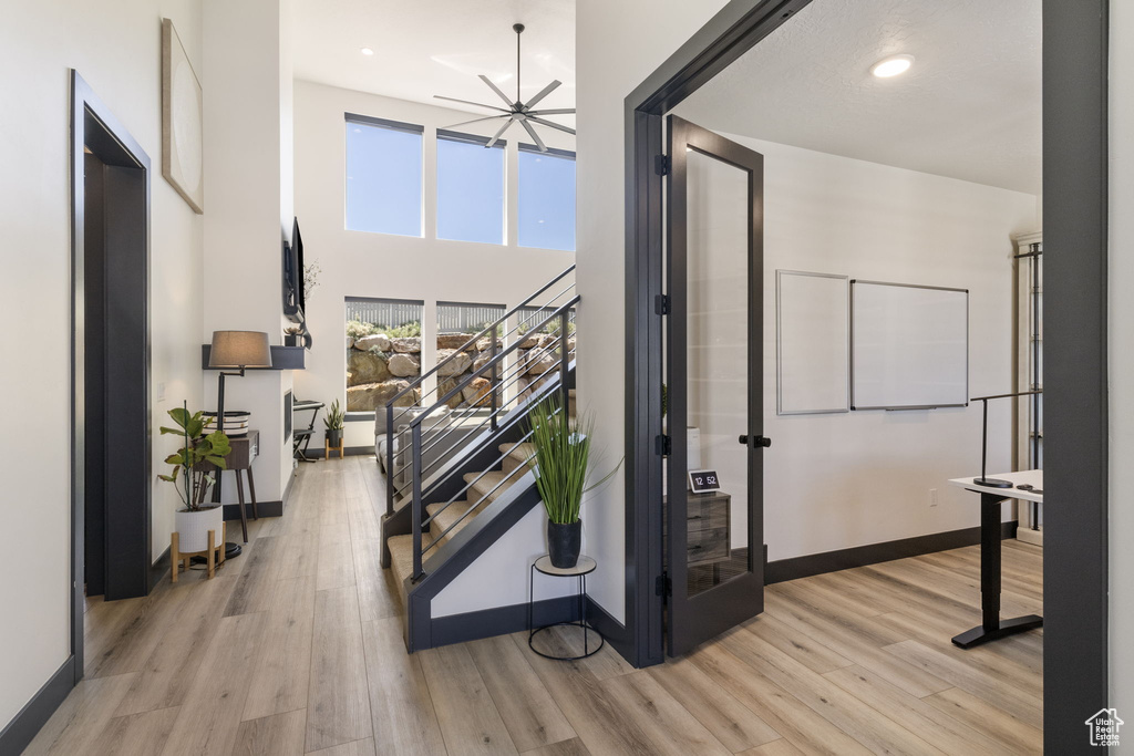 Hall featuring stairs, baseboards, a high ceiling, recessed lighting, and light wood-style flooring
