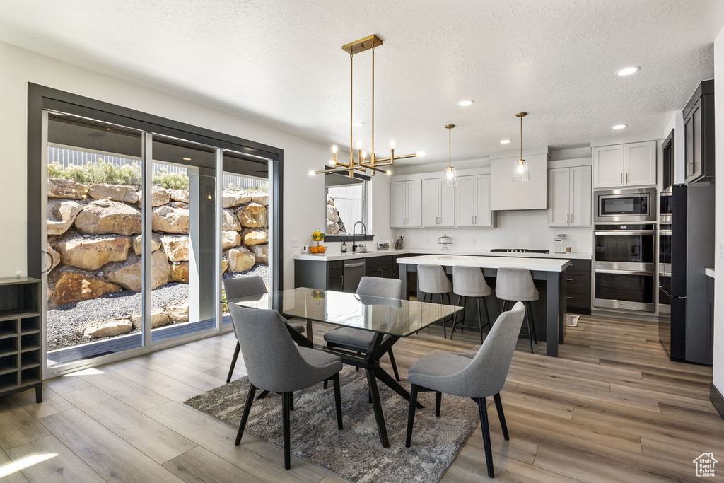 Dining area featuring light wood-type flooring, recessed lighting, a textured ceiling, and a notable chandelier