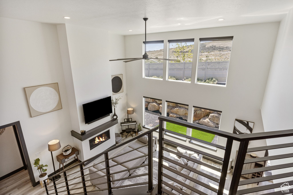 Living room with recessed lighting, ceiling fan, wood finished floors, and a lit fireplace