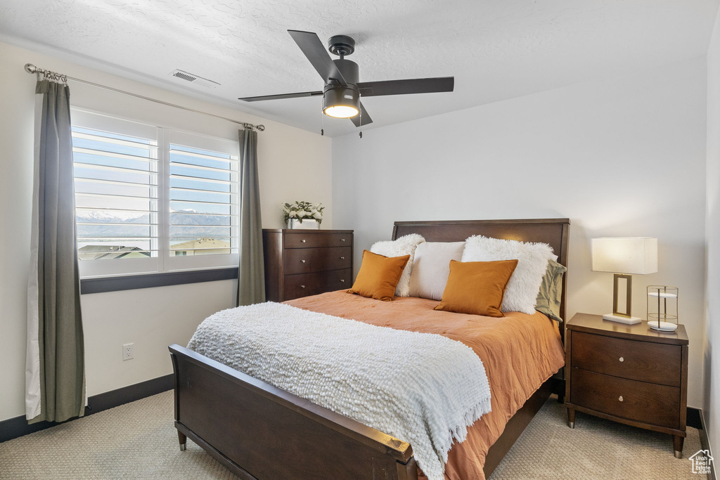 Bedroom featuring light colored carpet, a textured ceiling, a ceiling fan, baseboards, and visible vents