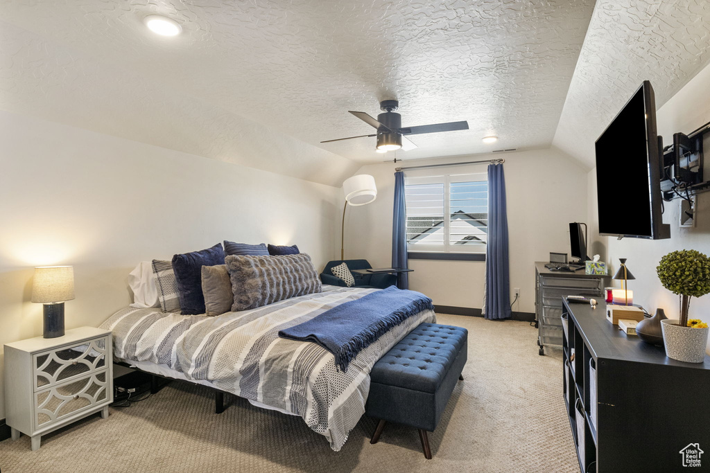 Bedroom featuring ceiling fan, light colored carpet, a textured ceiling, baseboards, and lofted ceiling