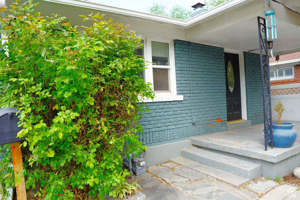 Doorway to property with brick siding and a porch