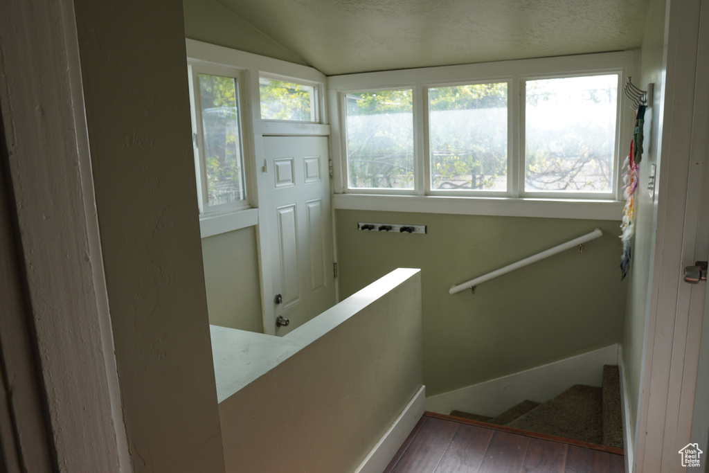 Staircase with a healthy amount of sunlight, baseboards, vaulted ceiling, and hardwood / wood-style floors