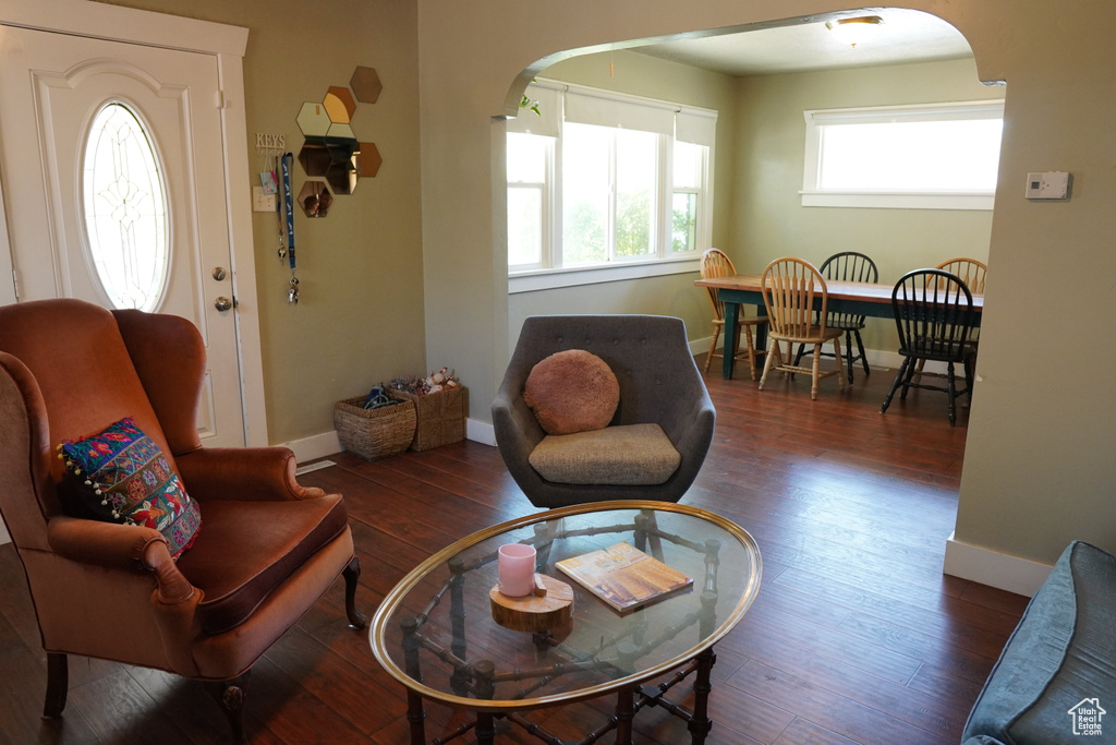 Living area featuring arched walkways, baseboards, and wood finished floors