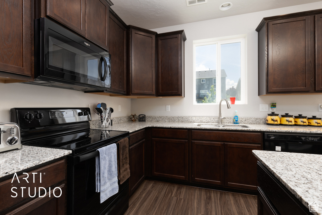 Kitchen featuring black appliances, a sink, dark wood-style flooring, dark brown cabinetry, and light stone counters
