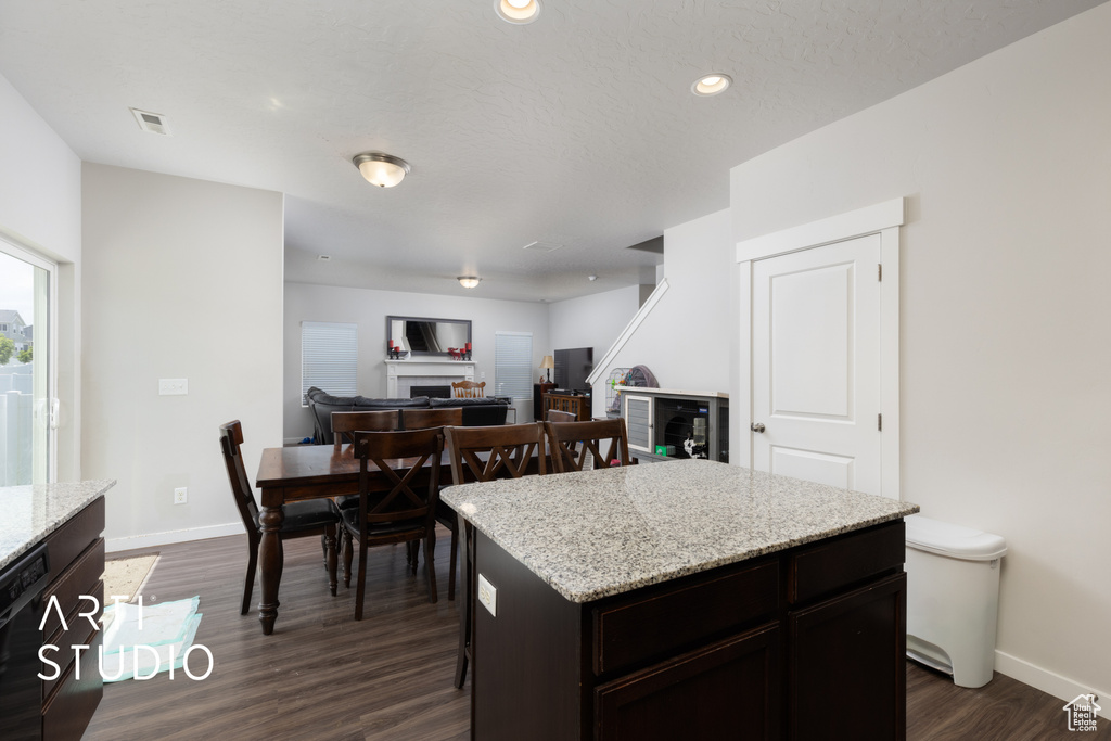 Kitchen featuring a fireplace, dark wood-style floors, baseboards, a center island, and recessed lighting