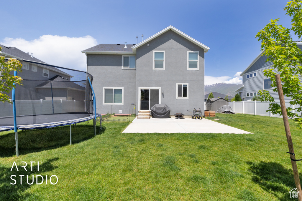 Back of property with a trampoline, a patio, stucco siding, and entry steps