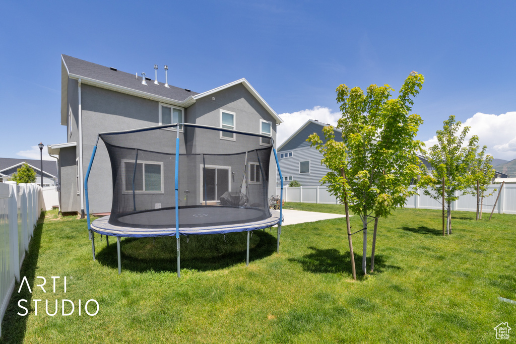 Back of property with a trampoline and stucco siding