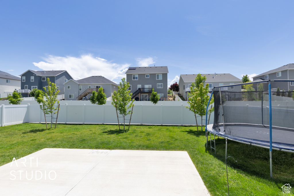 View of yard featuring a trampoline, a residential view, and a patio area