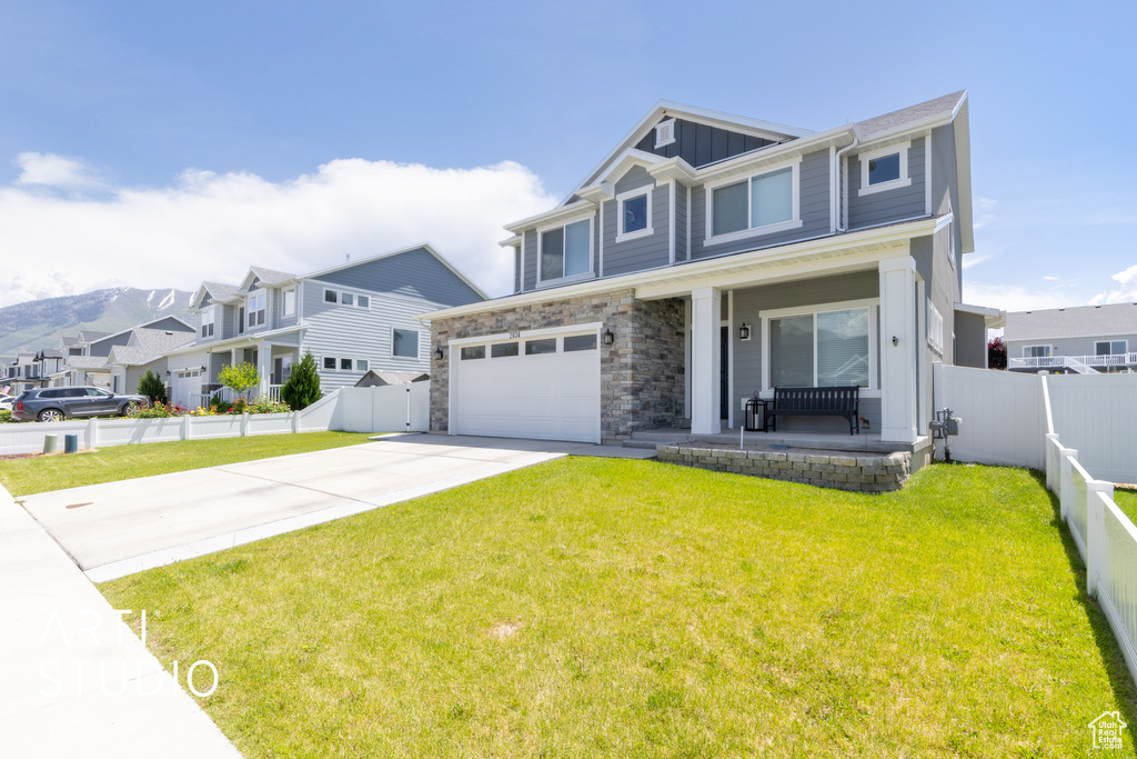 Craftsman-style home with a porch, board and batten siding, driveway, a garage, and a residential view