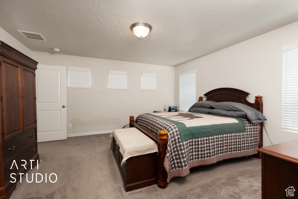 Carpeted bedroom featuring a textured ceiling and baseboards