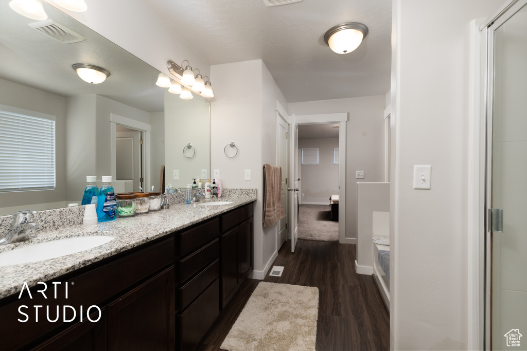 Bathroom featuring wood finished floors, double vanity, and baseboards