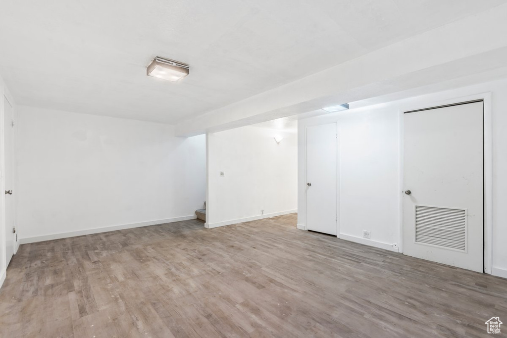 Finished basement featuring baseboards, visible vents, and wood finished floors