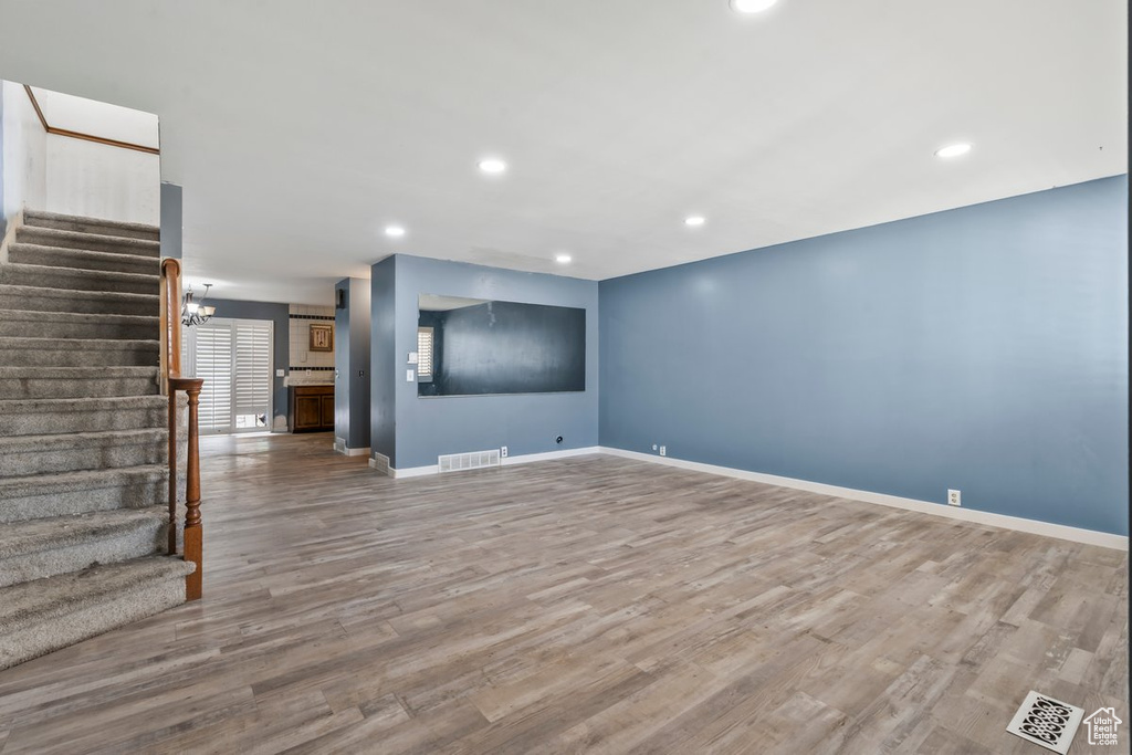 Unfurnished living room featuring baseboards, stairs, visible vents, and wood finished floors