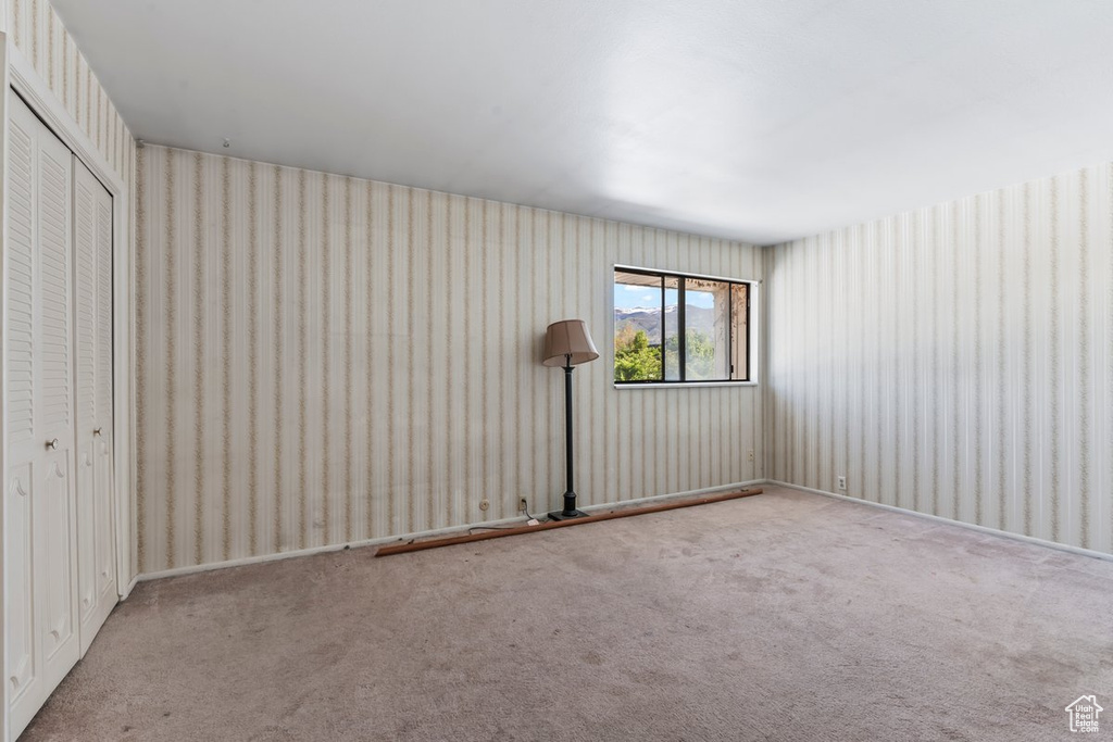 Unfurnished bedroom with a closet, wallpapered walls, and carpet floors