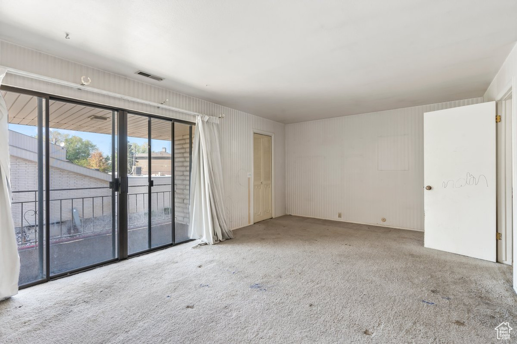 Carpeted spare room featuring visible vents