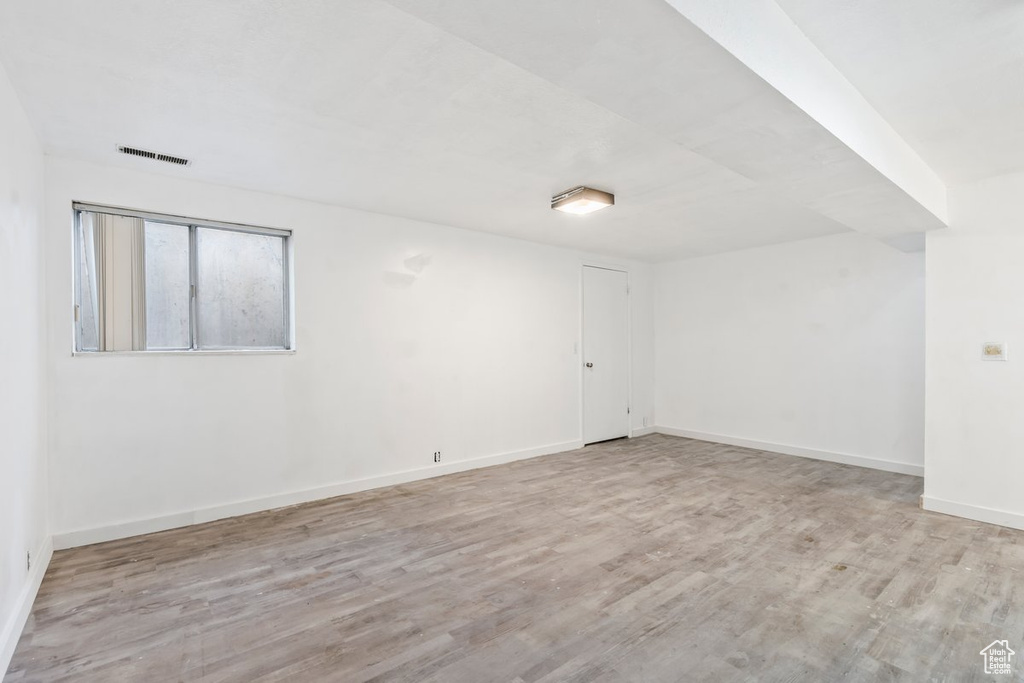 Empty room with baseboards, visible vents, and wood finished floors