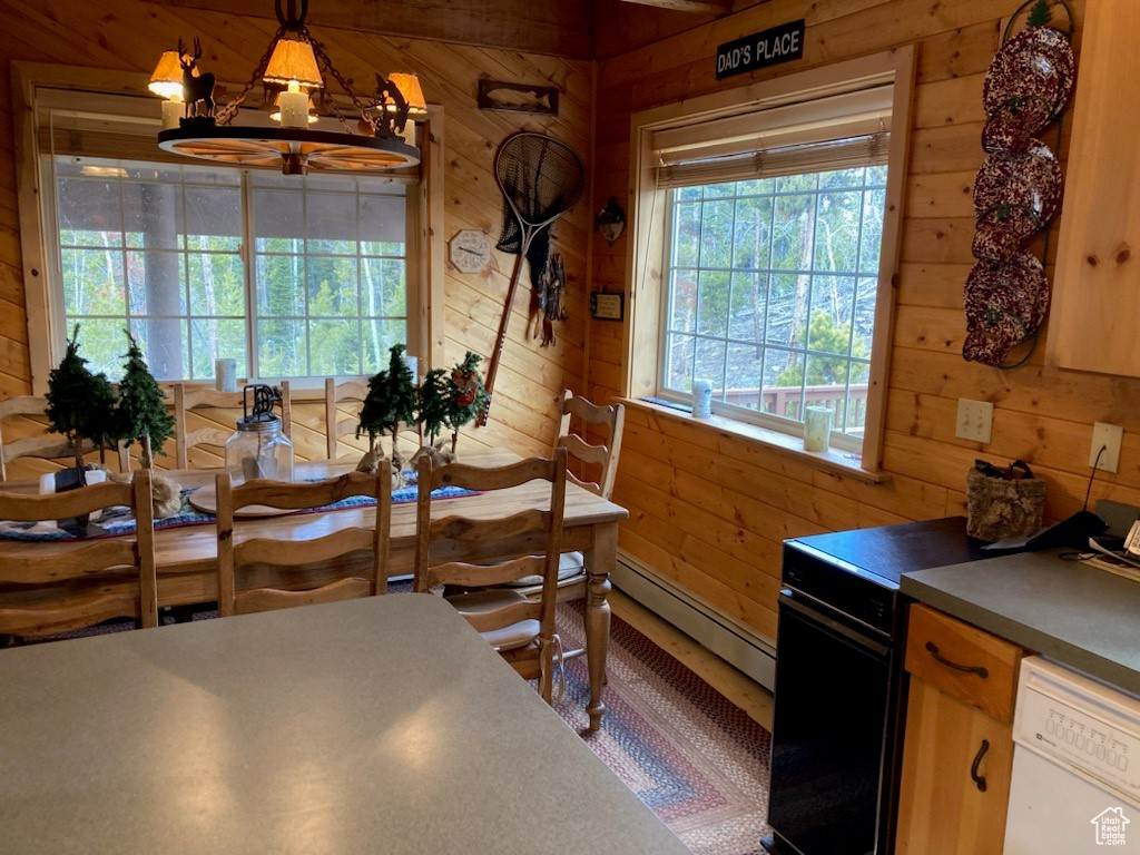 Dining space with a notable chandelier, baseboard heating, and wood walls