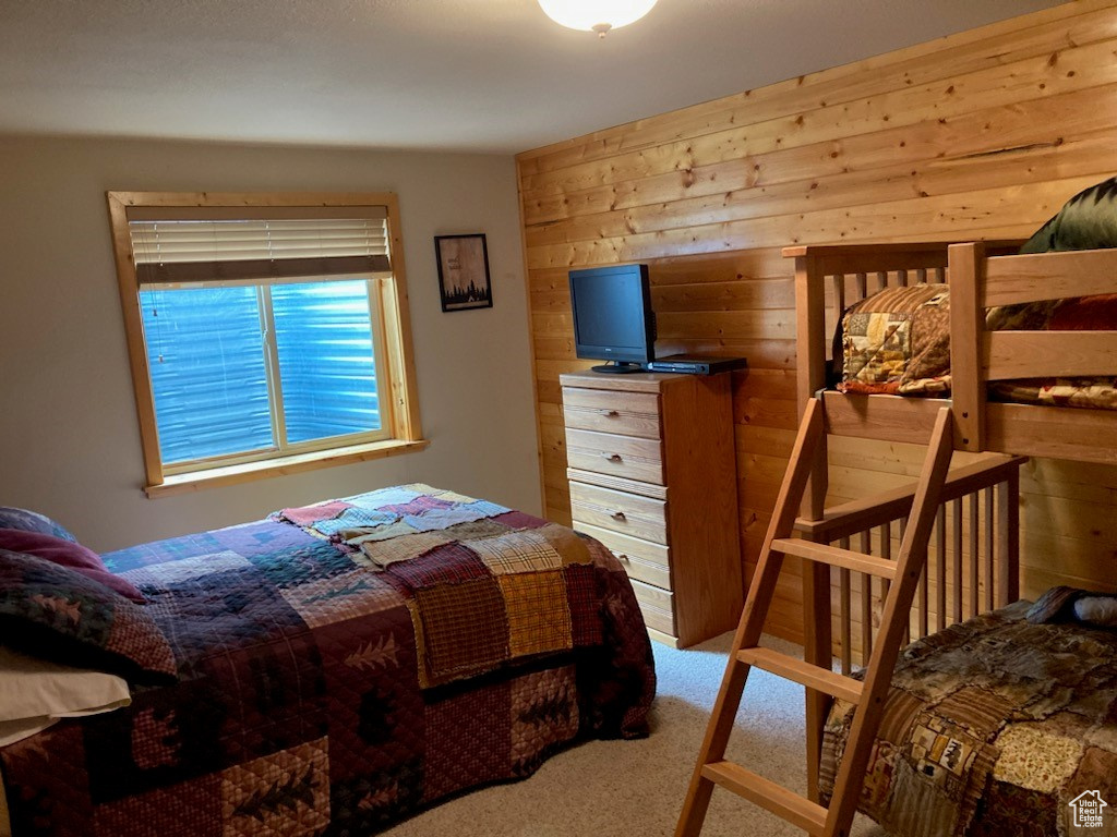 Carpeted bedroom featuring wooden walls