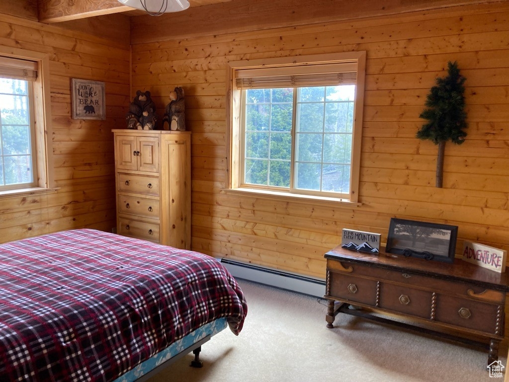 Carpeted bedroom with wood walls and a baseboard radiator