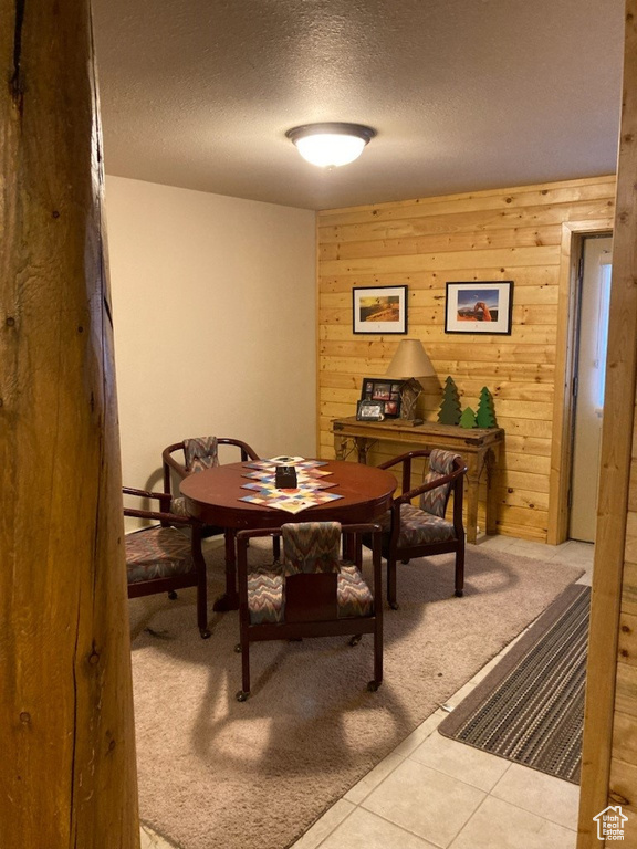 Dining area featuring a textured ceiling, carpet flooring, and wooden walls