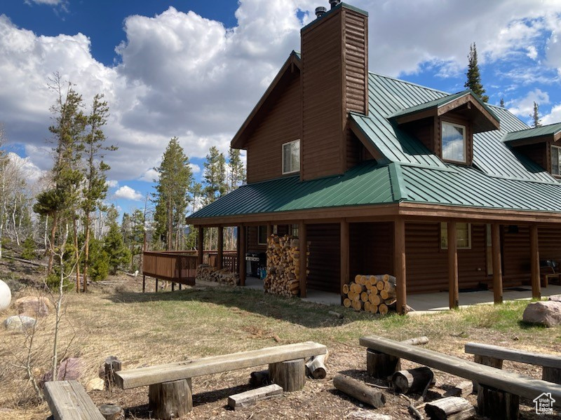 View of property exterior with a chimney, metal roof, faux log siding, and a standing seam roof