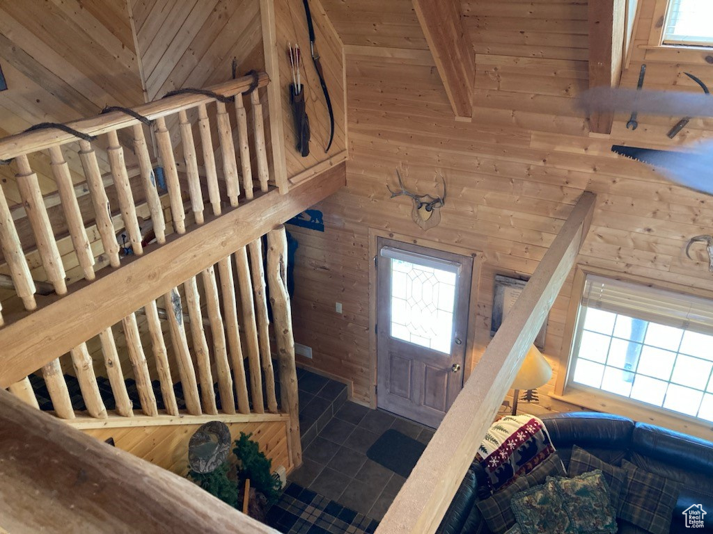 Stairway with plenty of natural light, wooden ceiling, and wooden walls