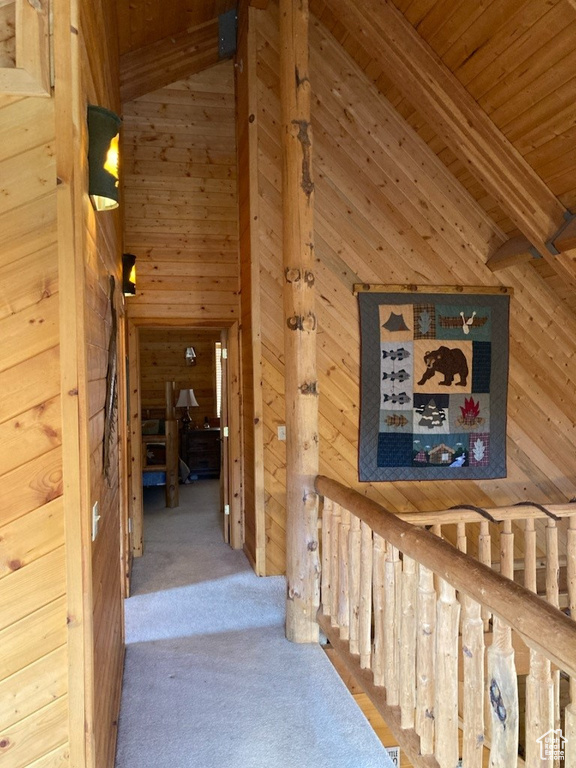 Corridor featuring wooden ceiling, wooden walls, vaulted ceiling with beams, and carpet floors