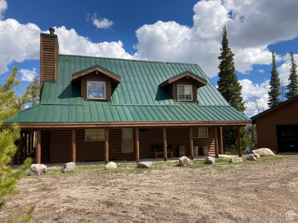View of front of house featuring metal roof, a standing seam roof, and a chimney