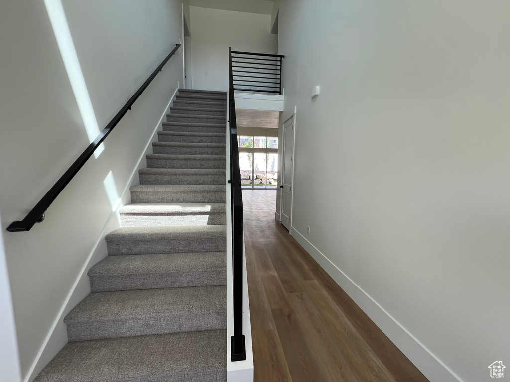 Staircase with wood finished floors and a high ceiling