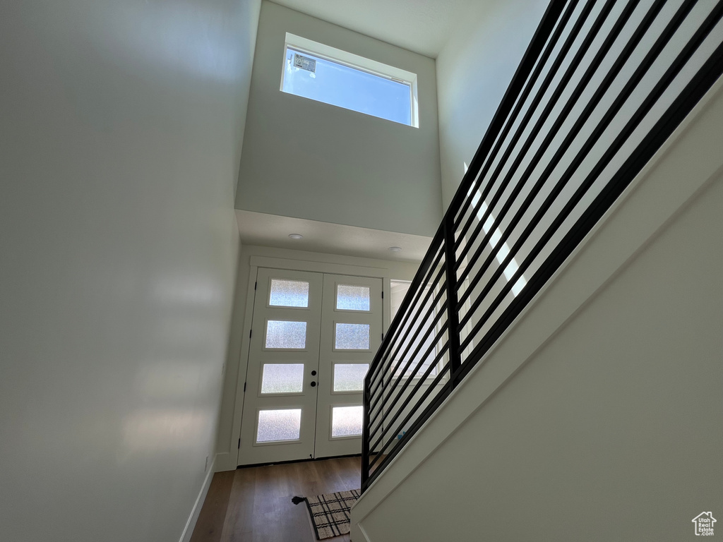 Entrance foyer with stairs, a high ceiling, french doors, and wood finished floors