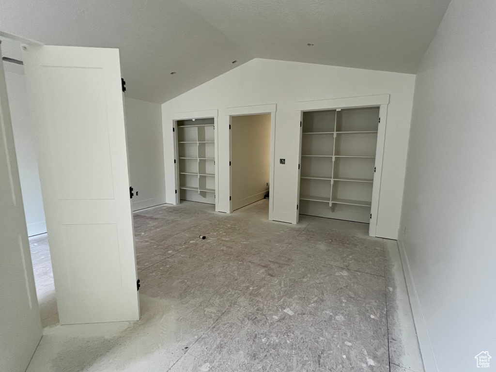 Unfurnished bedroom with lofted ceiling and multiple closets