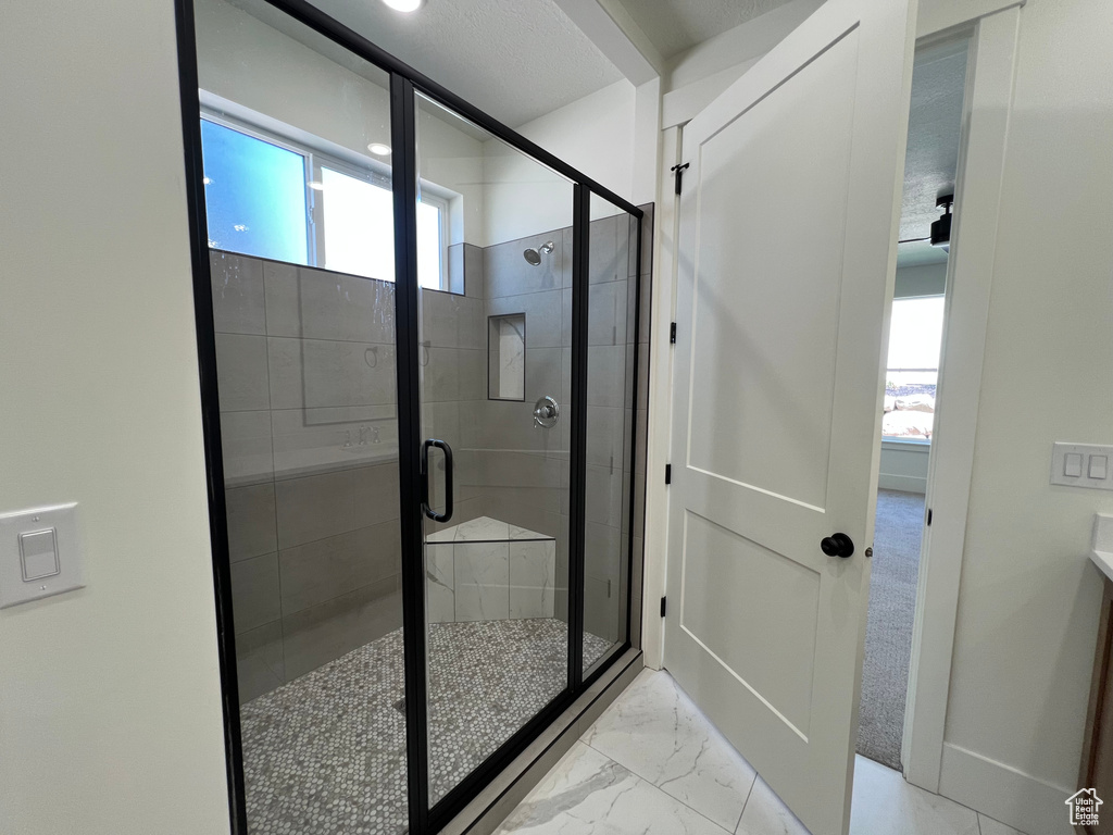 Full bathroom featuring a stall shower and marble finish floors